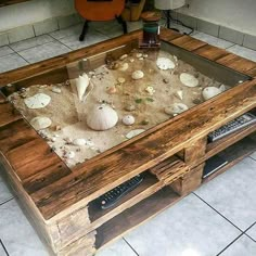 a coffee table made out of wood and glass with shells in it on the floor