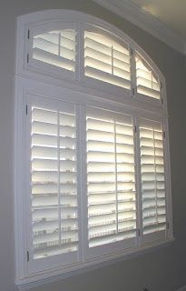 an arched window with white shutters in a room