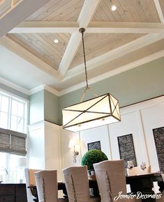 a dining room table and chairs in front of a chandelier hanging from the ceiling