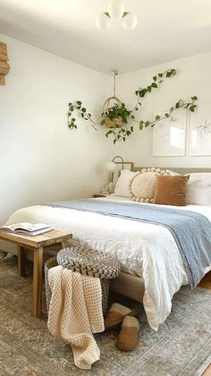 a bedroom with a bed, rug and plant hanging on the wall over it's headboard