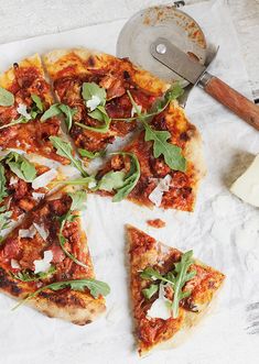 a pizza sitting on top of a white table next to a knife and spatula