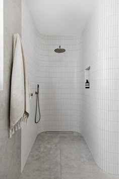 a white tiled bathroom with a shower head and hand held shower faucet in the corner