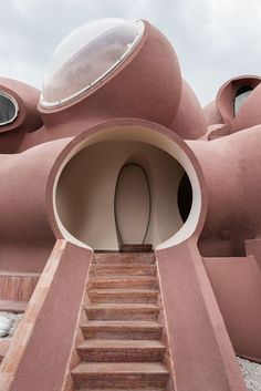 an unusual building with stairs leading up to the entrance and round windows on each side