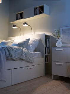 a bed with white sheets and pillows in a room next to a book shelf filled with books