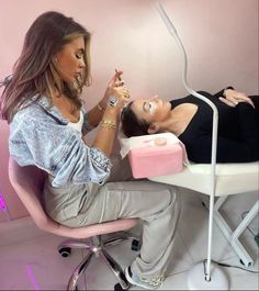 a woman getting her teeth brushed by a professional hair stylist in a pink room