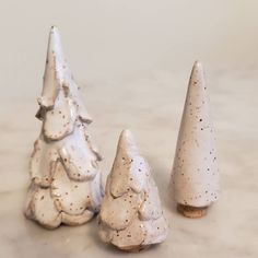 three ceramic christmas trees sitting on top of a marble countertop next to each other