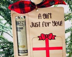 a christmas ornament hanging from a tree with money in the front and a red bow on top