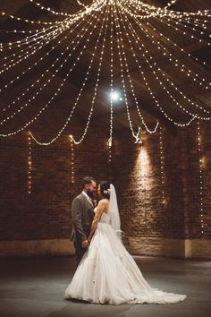 a bride and groom standing in front of a large chandelier