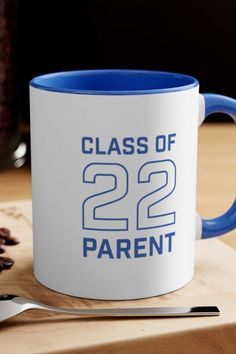 a blue and white coffee mug sitting on top of a wooden table next to a spoon