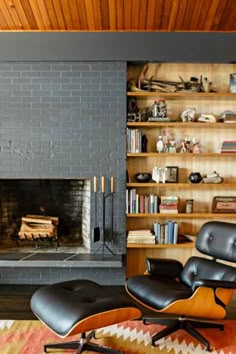 an eames lounge chair and ottoman in front of a fireplace with bookshelves