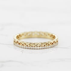 a yellow gold band with white diamonds on the inside and outside, sitting on a marble surface