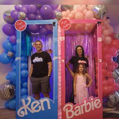 two adults and a child standing in front of an open barbie photo booth with balloons