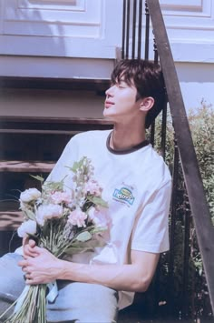 a young man sitting on the steps holding flowers