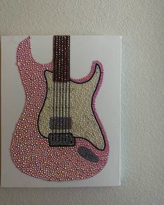 a painting of a guitar with pink and white dots on it's body is hanging on the wall