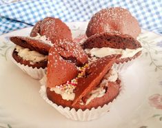 three chocolate cupcakes with white frosting and sprinkles on a plate