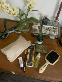 a wooden table topped with lots of beauty products and flowers next to a vase filled with white flowers