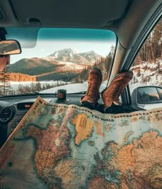 a person sitting in the back seat of a car looking at a map and mountains