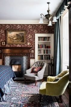 a bedroom with a bed, chair, fireplace and bookshelf on the wall