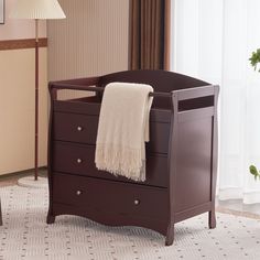 a baby crib with a blanket hanging from it's top and drawers below