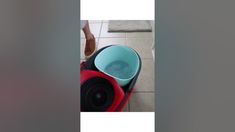 a person standing next to a red and black blow dryer on top of a tiled floor