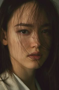 a woman with freckled hair looking at the camera while she is wearing a white shirt