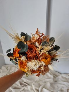 a person holding a bouquet of flowers on top of a bed