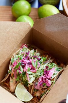 an open box filled with food sitting on top of a table next to limes