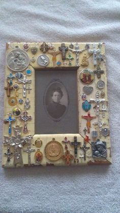 an old photo frame with many different types of buttons and crosses in it on a bed