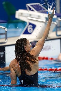 a women who is in the water with her arm up and one hand raised above her head