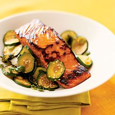 a white bowl filled with grilled salmon and cucumbers