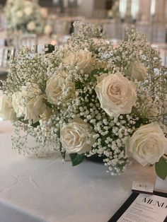 a bouquet of white flowers sitting on top of a table next to a menu card