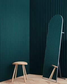 a chair and stool are in front of a green wall with vertical slats on it