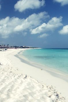 a sandy beach with blue water and white sand