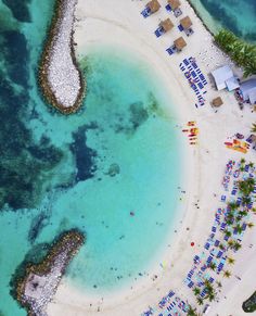 an aerial view of a sandy beach with blue water and umbrellas in the sand