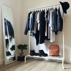 a clothes rack with shoes and jackets hanging on it next to a mirror in a room