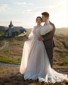 a man and woman standing next to each other on top of a grass covered field