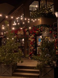 christmas decorations and lights decorate the outside of a store front at night with stairs leading up to it