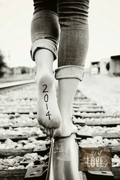 a person standing on train tracks with their feet in the air and writing on them