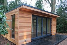 a small wooden building sitting on top of a wooden deck next to trees and bushes