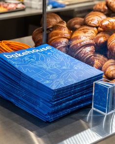 stacks of blue business cards sitting on top of a counter next to croissants