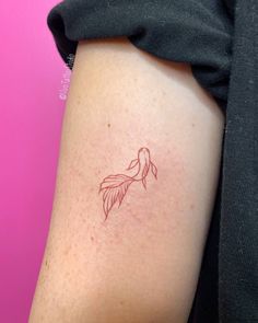 a woman's arm with a small tattoo of a fish on the left side