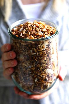 a person holding a jar full of granola