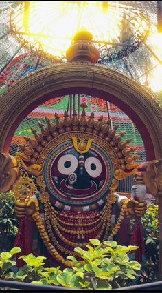 an elaborately decorated statue in the center of a garden with lots of greenery