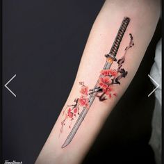 a knife with flowers on the arm and behind it is a flower tattoo that has been done by an artist