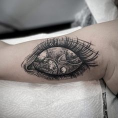 an eye tattoo on the arm with space and planets in it's irise