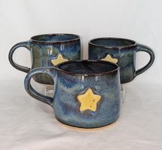 three coffee mugs with gold stars on them sitting side by side in front of a white background