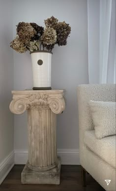 a vase filled with flowers sitting on top of a table next to a white chair