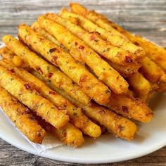 french fries on a white plate sitting on a wooden table