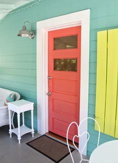 the front door is painted bright red and yellow, while the side table has two white chairs