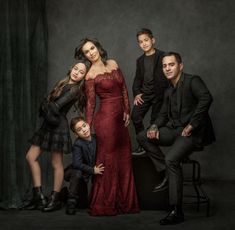 a family posing for a photo in front of a dark background, with one child and two adults